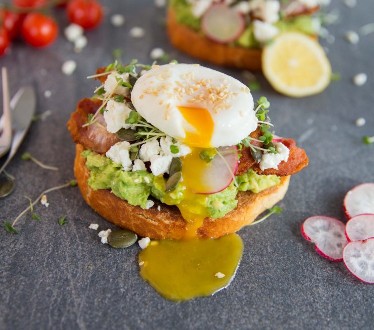 Cafe Style Smashed Avocado on Toast smashed avocado on toast with yolk pouring out of poached egg on top