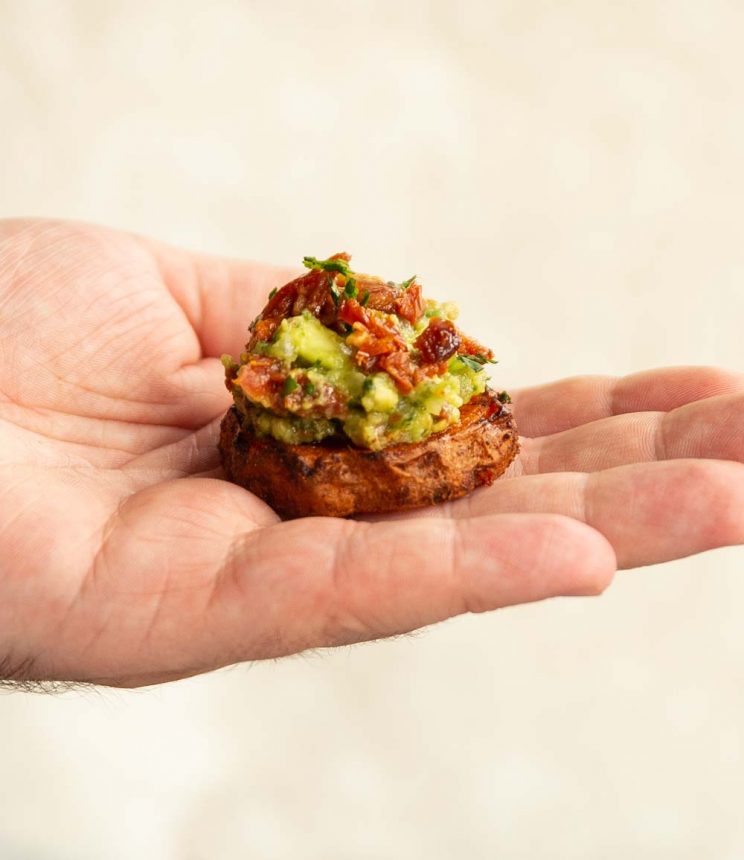 Sweet Potato Bites mini sweet potato bite in palm on hand against white backdrop