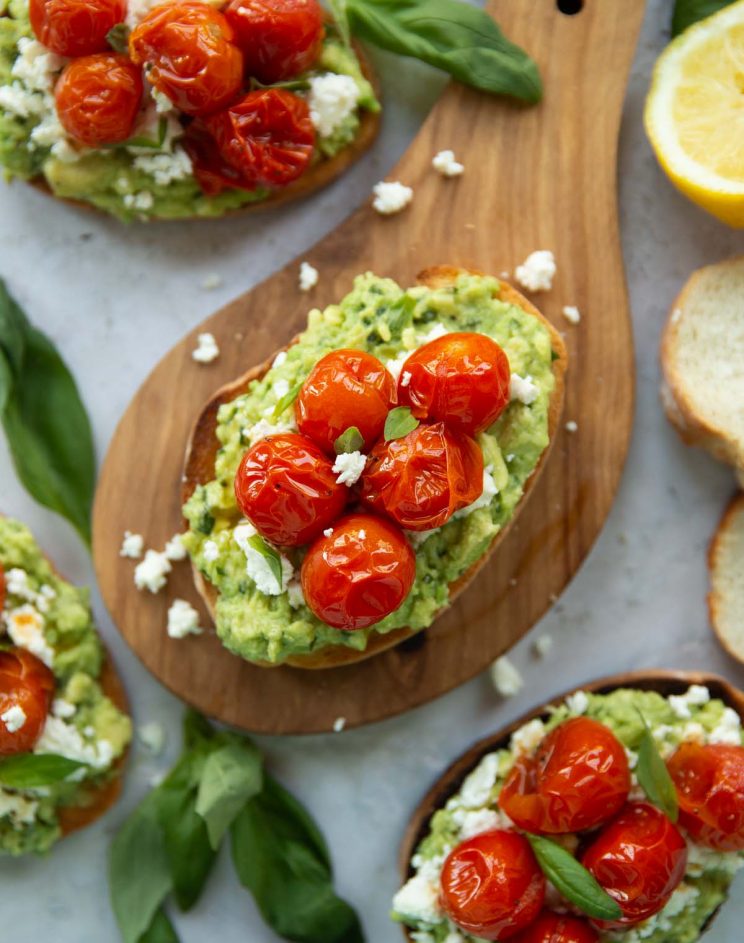 Tomato Avocado Toast overhead shot of toast on wooden board surrounded by toast and garnish