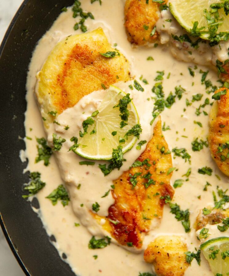 coconut lime chicken close up overhead shot of coconut lime chicken in pan garnished with lime and coriander