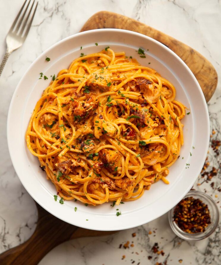 creamy tomato salmon pasta overhead shot of creamy tomato salmon pasta in large white bowl on wooden chopping board