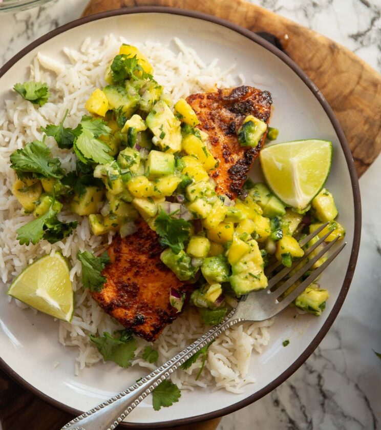 chipotle salmon served with avocado mango salsa chipotle salmon served with avocado mango salsa on small white plate with rice