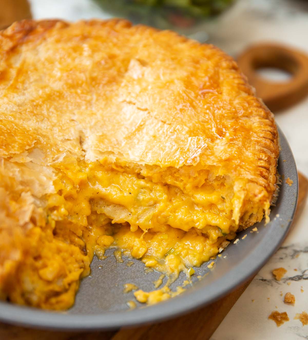 close up shot of cheese potato onion pie in dish with slice taken out
