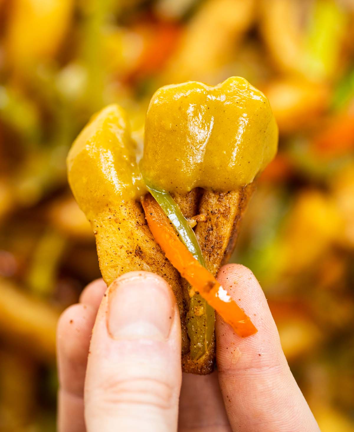 close up shot of hand holding salt and chilli chips dunked in curry sauce