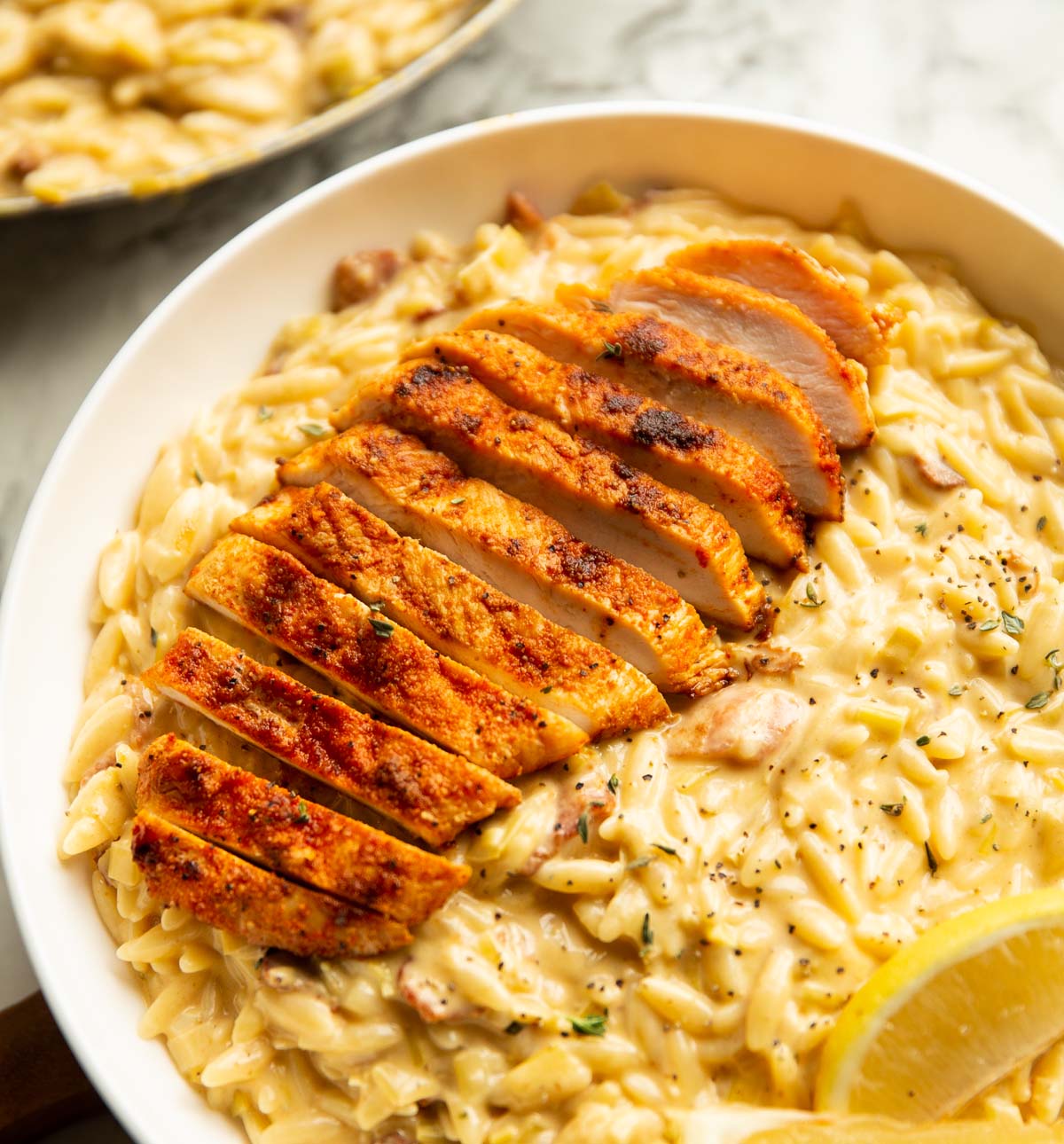 close up shot of chicken bacon leek orzo in large white dish