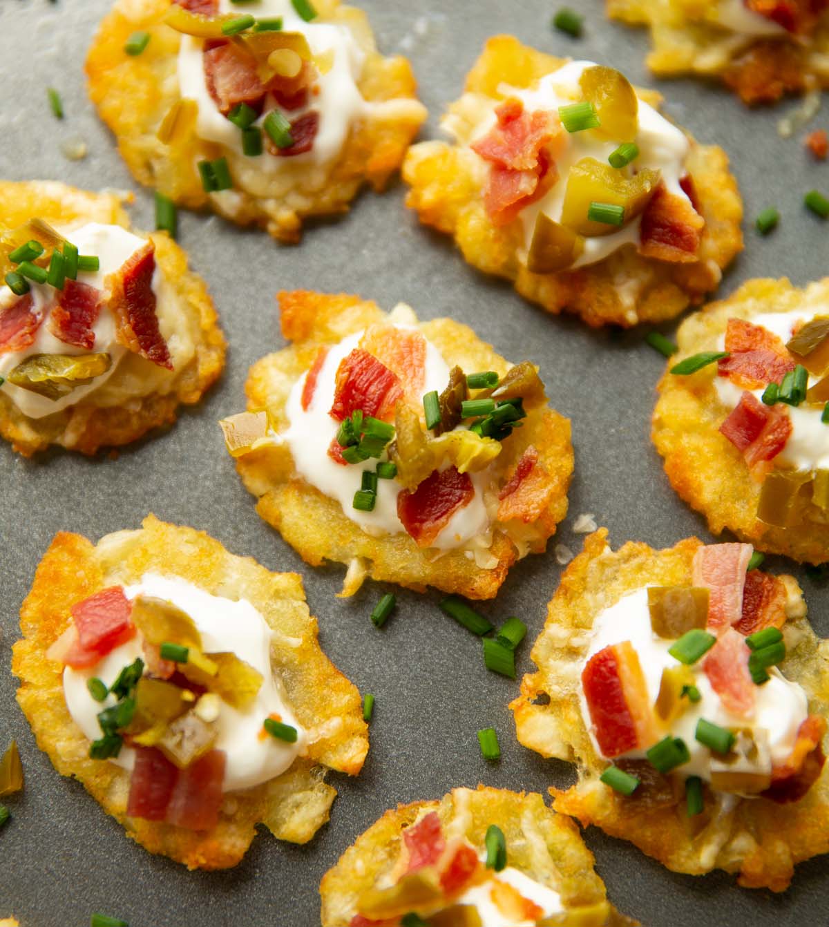 close up shot of loaded smashed tater tots on grey tray